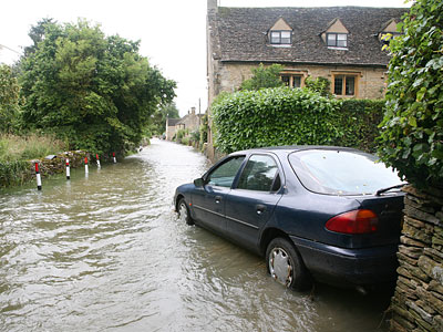 Ein überfluteter Straßenabschnitt mit einem stehen gebliebenen Auto.